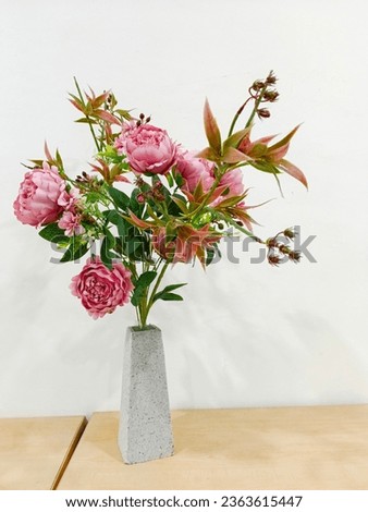 Minimalist bouquet of white tulips, pink eustoma, hyacinth, eucalyptus in a fluted glass vase on the white panel of the artificial fireplace.