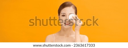 Young healthy woman with beautiful clear skin holding cotton pads on banner background