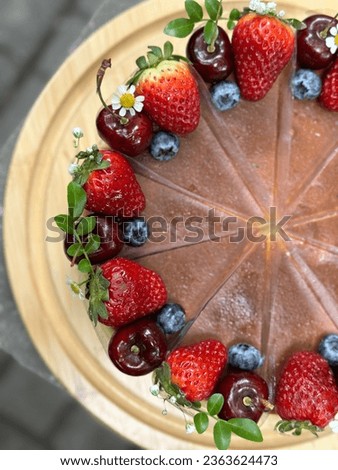 Top view delicious Mixed berry cream cheese cake. 
cheesecake on a wooden plate. Fresh  Strawberry, Blueberry, Cherry topping with white daisy flower and thyme leaves. Picture free space for text.