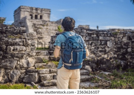 Male tourist enjoying the view Pre-Columbian Mayan walled city of Tulum, Quintana Roo, Mexico, North America, Tulum, Mexico. El Castillo - castle the Mayan city of Tulum main temple Royalty-Free Stock Photo #2363626107