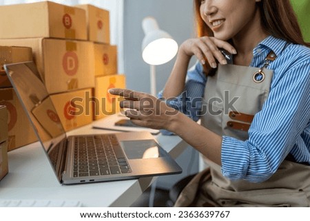 Small business start-up, SME owner, female entrepreneur working on packaging parcels. Receipt and check orders online to prepare boxes for sale to customers, online SME business concept.
