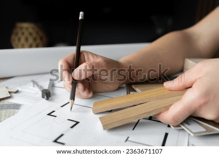 Female interior designer showing wooden slats lamella panels samples in a design studio. Woman showcasing assortment of wood materials, textures, color options and structural blueprint projects plans. Royalty-Free Stock Photo #2363671107