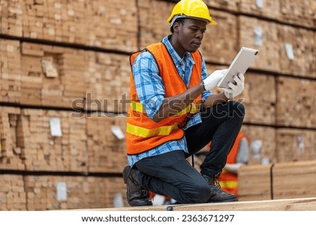 African workers man engineering walking and inspecting with working suite dress and hand glove in timber wood warehouse. Concept of smart industry worker operating. Wood factories produce wood palate.