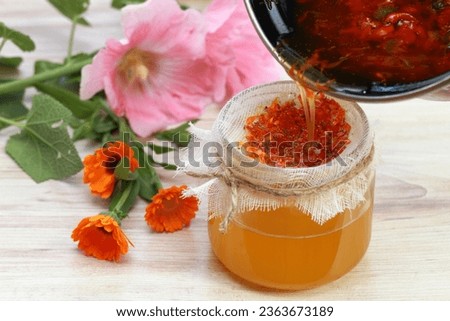 Natural herbal ointment, filtering medicinal cream from  marigold flowers. Calendula cream good for better skin, Calendula officinalis  in front,  Alcea rosea at back.