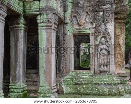 Moss-covered stone carvings on a building wall at Ta Prohm Tomb Raider temple complex. Angkor Wat historical site, Siem Reap, Cambodia Royalty-Free Stock Photo #2363673905