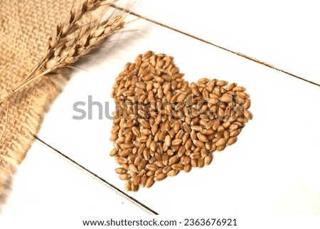 A cute heart shape designed with wheat grains on a wooden table.