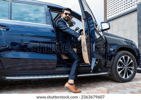 Handsome successful rich indian businessman in formal wear and sunglasses getting out of his luxurious car. Royalty-Free Stock Photo #2363679607