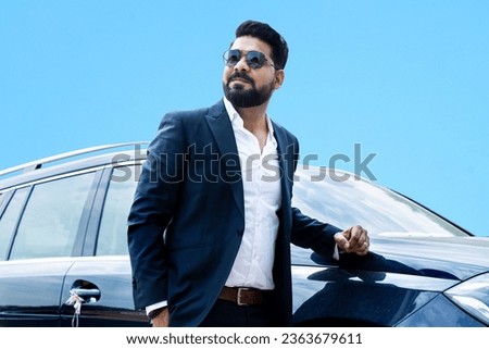 Handsome successful rich indian businessman in formal wear and sunglasses standing next to his car. Royalty-Free Stock Photo #2363679611