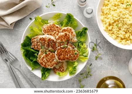 Chicken patties, cutlets with fresh romaine lettuce salad and couscous, top down view Royalty-Free Stock Photo #2363681679