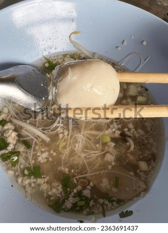 a photography of a bowl of soup with chopsticks and a spoon, consommead soup with a spoon and a spoon in it.