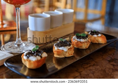 Mini brioche toast with creme fraiche and black sturgeon caviar with a colorful interior at a luxury restaurant, the Carre d Or, Nice, South of France Royalty-Free Stock Photo #2363693351