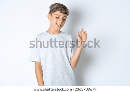 Overjoyed successful beautiful teenager boy wearing casual grey T-shirt raises palm and closes eyes in joy being entertained by friends