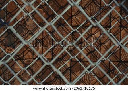 Chain link iron net with stack of wooden planks behind