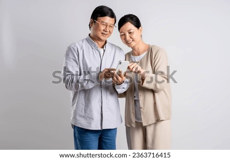 Portrait of middle-aged Asian couple using phone  on a white background