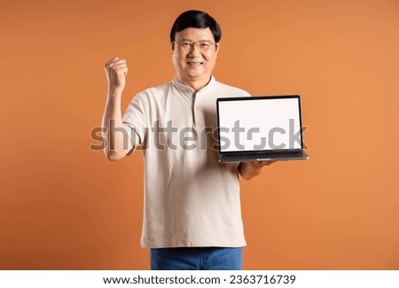 Portrait of middle-aged Asian man using laptop on brown background