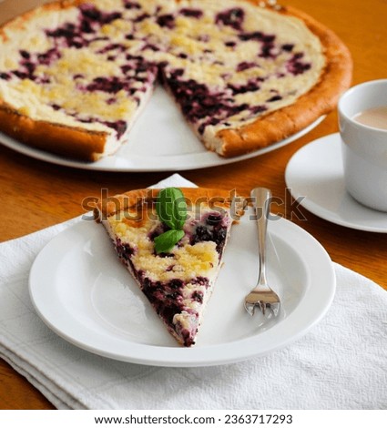 Piece of traditional Wallachian blueberry pie called "frgal" on a white plate. Traditional Moravian sweet dessert on wooden table. Typical Czech cuisine concept. Summer fruit cake. Selective focus. Royalty-Free Stock Photo #2363717293