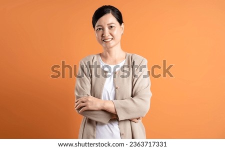 Portrait of middle age Asian woman posing on brown background Royalty-Free Stock Photo #2363717331
