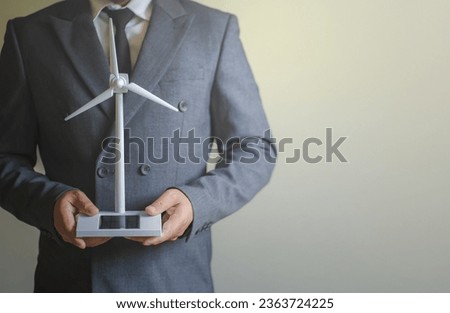 Portrait of a male architect or engineer holding a small windmill. solar panel The concept of sustainability in renewable energy Clean energy design and generation
