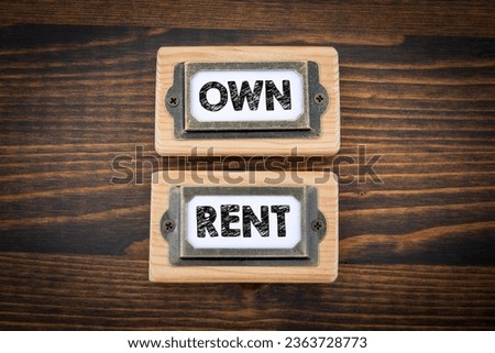 OWN and RENT. File cabinet labels. Dark wooden background.