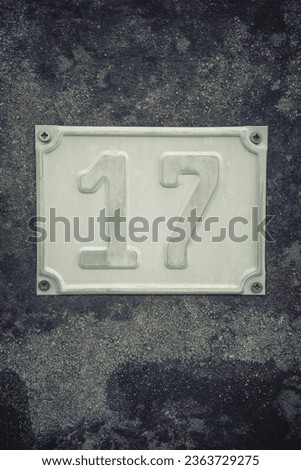 Close up shot a metal plate showing house number 17.