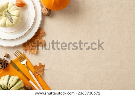 Craft the perfect Thanksgiving message. Top-down view shot of tableware, orange napkin, pumpkin accents, and seasonal ornaments, such as maple leafage on beige tablecloth background Royalty-Free Stock Photo #2363730671