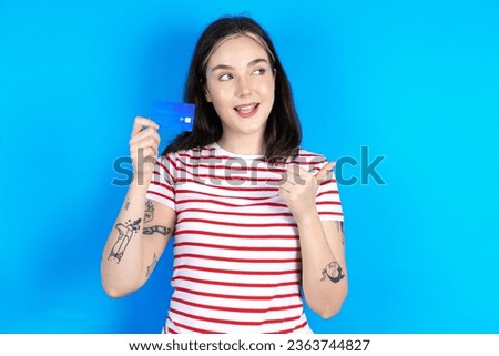 Young beautiful woman wearing striped T-Shirt hold credit card point empty space