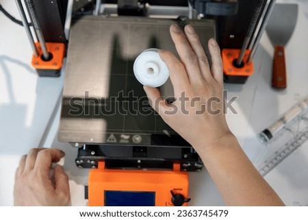 Man checking 3d printer, process of making things on 3d printer in laboratory.
