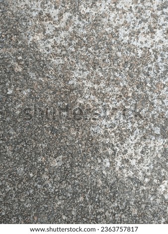 portrait of a photo of a cement surface that is white on the right side of the photo and black on the left side as seen from above.