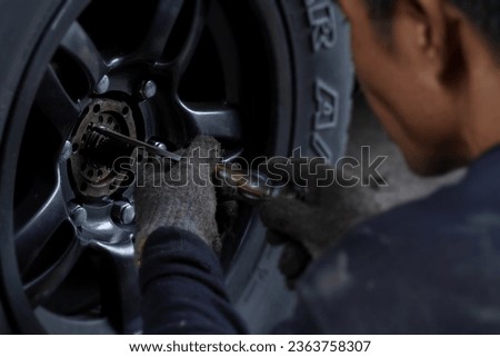 Close up photo of cars driving system repairing. Man mechanician remove a screw from wheel hub to maintenance. Background for automobile or transportation.  Royalty-Free Stock Photo #2363758307