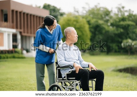 Elderly asian senior man on wheelchair with Asian careful caregiver. Nursing home hospital garden concept are walking in the garden. to help and encourage. green nature.
