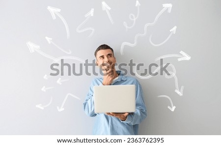 Thoughtful young man with laptop on light background. Concept of choice