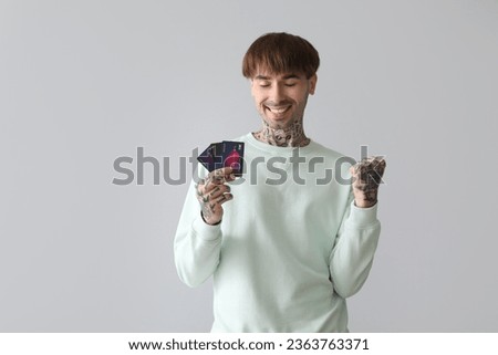 Happy young man with credit cards on light background