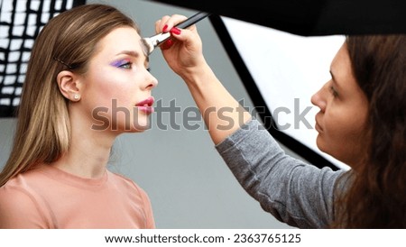 Backstage of the photo shoot: Make-up artist applies makeup on beautiful white  model. Tutorial makeup master class.