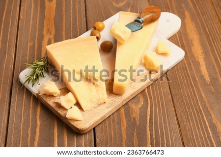 Board with pieces of tasty Parmesan cheese on wooden background
