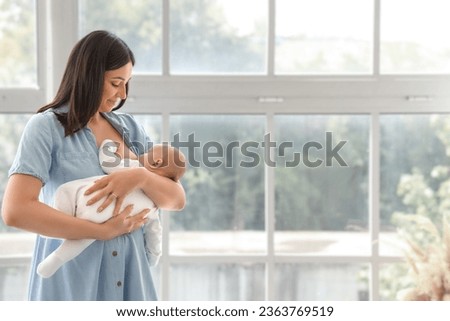 Young woman breastfeeding her baby at home Royalty-Free Stock Photo #2363769519