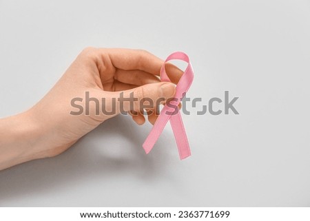 Woman with pink ribbon on grey background. Breast cancer awareness concept