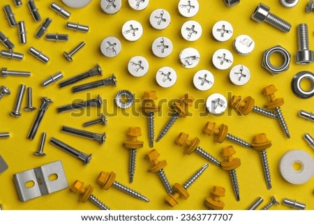 Many different fasteners on yellow background, flat lay Royalty-Free Stock Photo #2363777707
