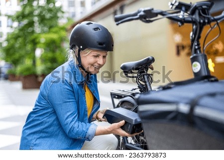 Mature woman changing battery on electric bicycle
