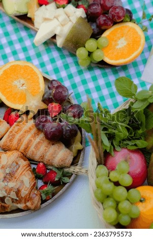 various fresh fruit arranged in compositions such as grapes, oranges, strawberries, kiwi, mint leaves, and added with croissants