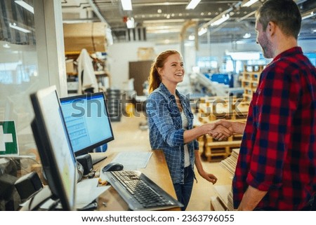 Two Caucasian coworkers congratulating each other while working in a warehouse Royalty-Free Stock Photo #2363796055