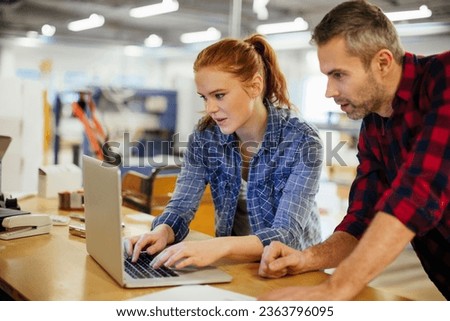 Diverse group of coworkers using a laptop in a printing press office Royalty-Free Stock Photo #2363796095