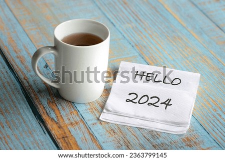Hello 2024 on piece of tissue next to a white cup of coffee. Royalty-Free Stock Photo #2363799145