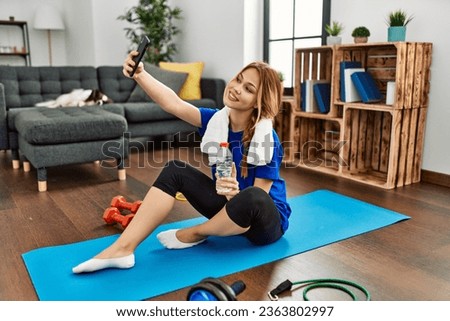 Young caucasian woman make selfie by smartphone sitting on floor at home