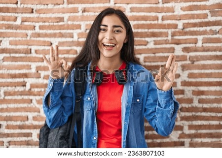 Young teenager girl wearing student backpack doing relax sign smiling and laughing hard out loud because funny crazy joke. 