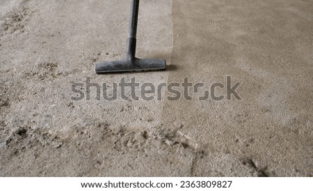 A worker vacuums the floor with an industrial vacuum cleaner. A male worker at a construction site cleans the concrete floor from dust with a vacuum cleaner after dirty work. 