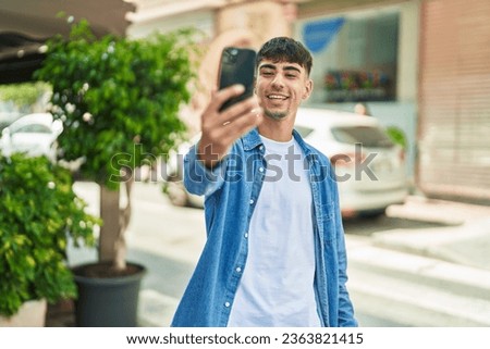 Young hispanic man smiling confident making selfie by the smartphone at street