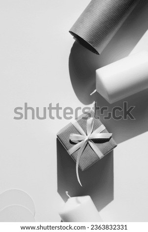Aesthetic Monochrome Christmas Still Life. New Year Flatlay. Ribbon Bow Decorated Gift, Candles on White Background.