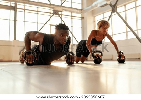 athletic african american couple in sports uniforms train and do push-ups in the gym, man trainer and woman go in for sports in the fitness room in the morning Royalty-Free Stock Photo #2363850687