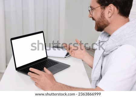 Man having video chat via laptop at white table indoors, selective focus