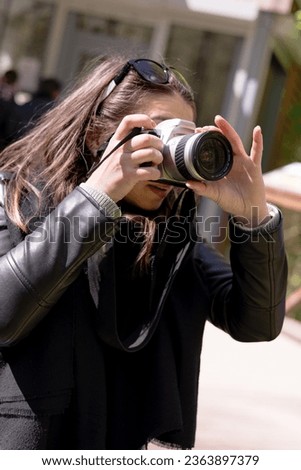 A young girl is holding a camera in her hands. Dark hair, autumn landscape. Concept woman photographer, women's art.
